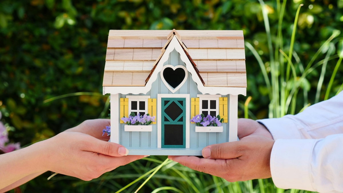 Two people holding a house in their hands.